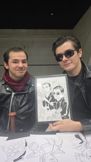 Deux personnes souriantes, l'une tenant un cadre avec un dessin.